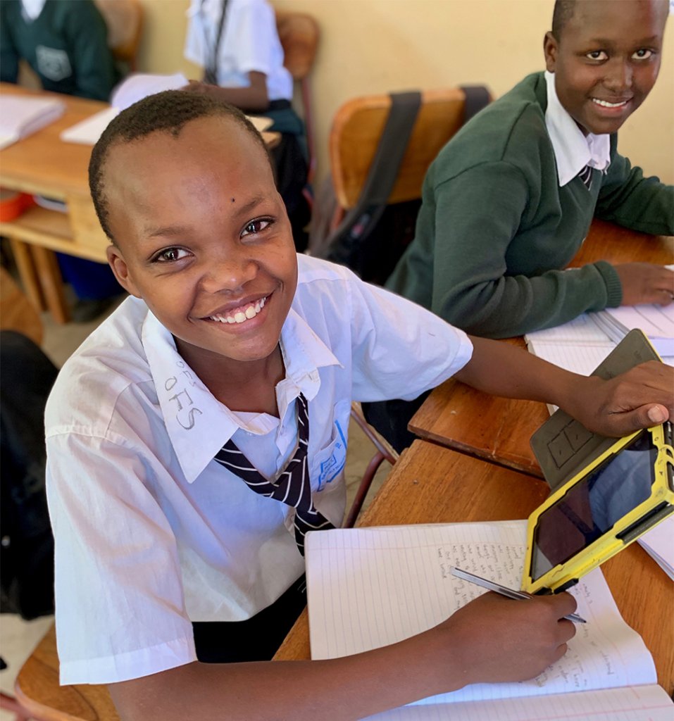 A smiling Mtakuja student holding a Quest Forward tablet.